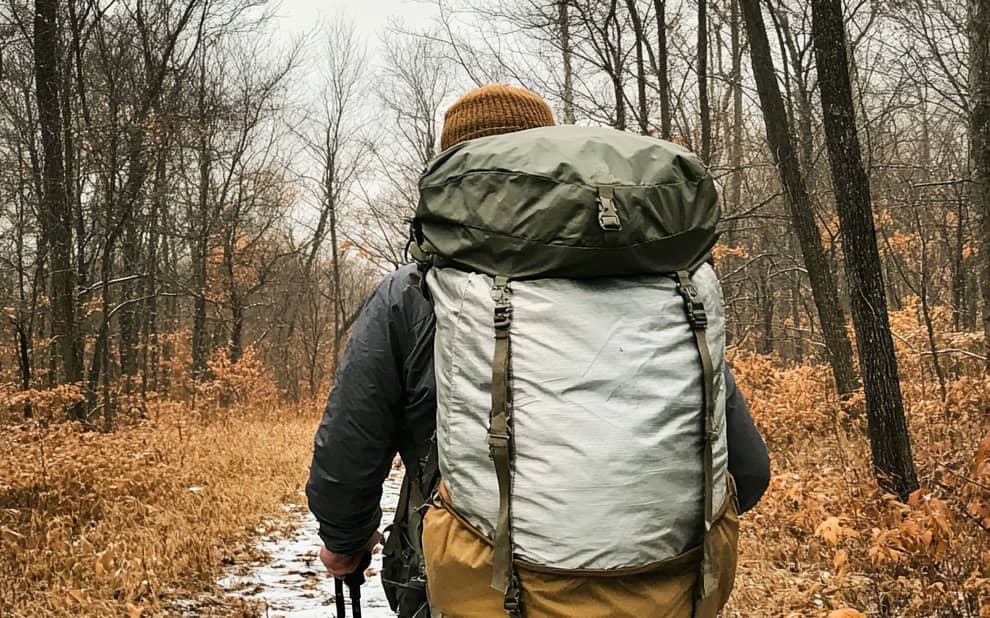 Une personne se promène dans une forêt avec un sac de randonnée
